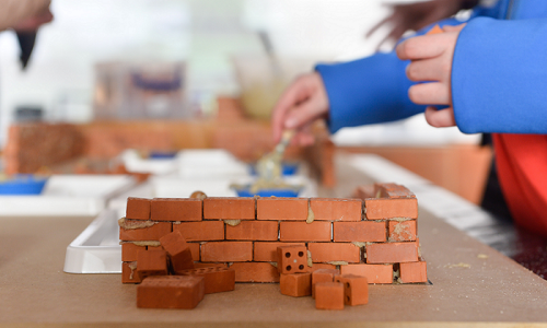 Children making a wall out of tiny toy bricks